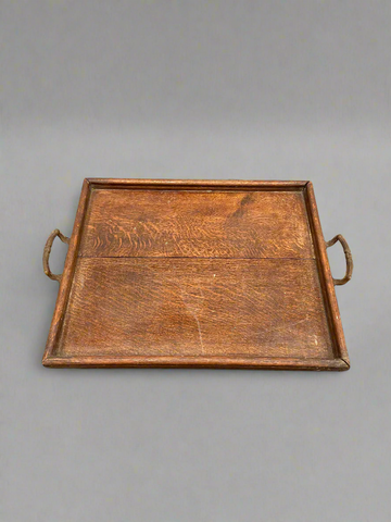 An antique, oak, square serving tray with curved brass handles.
