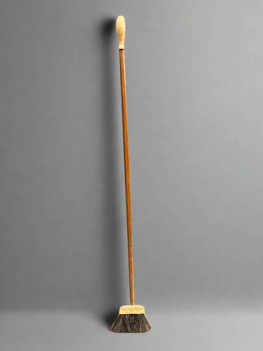 A matching set of small narrow brooms with long wooden handles.