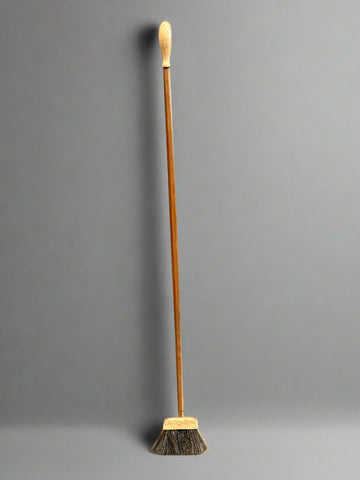 A matching set of small narrow brooms with long wooden handles.
