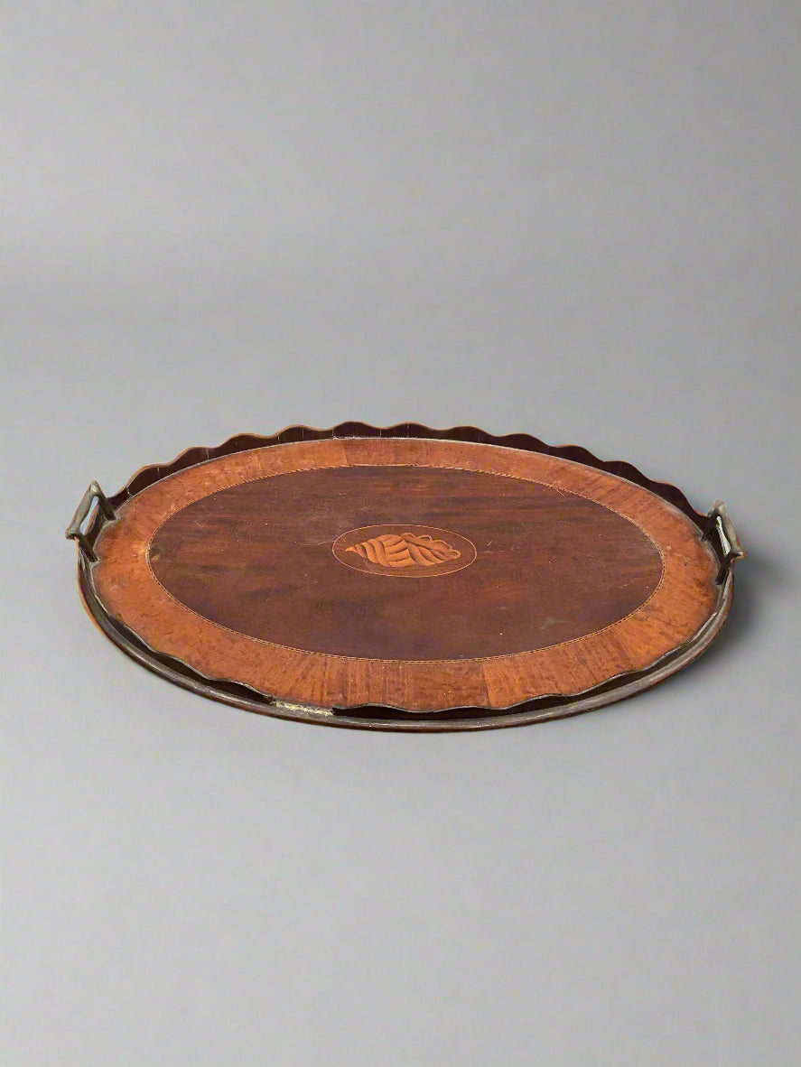 An antique scalloped-edge serving tray, featuring a central inlaid shell design.