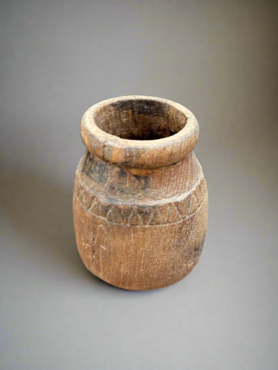 A vintage wooden paint brush holder pot with carved markings.