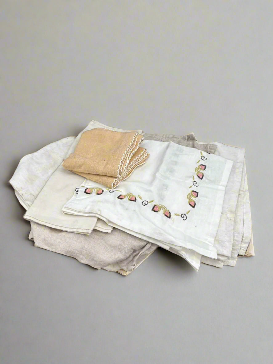 A bundle of miscellaneous embroidered home linens in neutral colours.