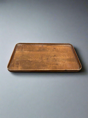 A rectangular, vintage, wooden serving tray with rounded edges.