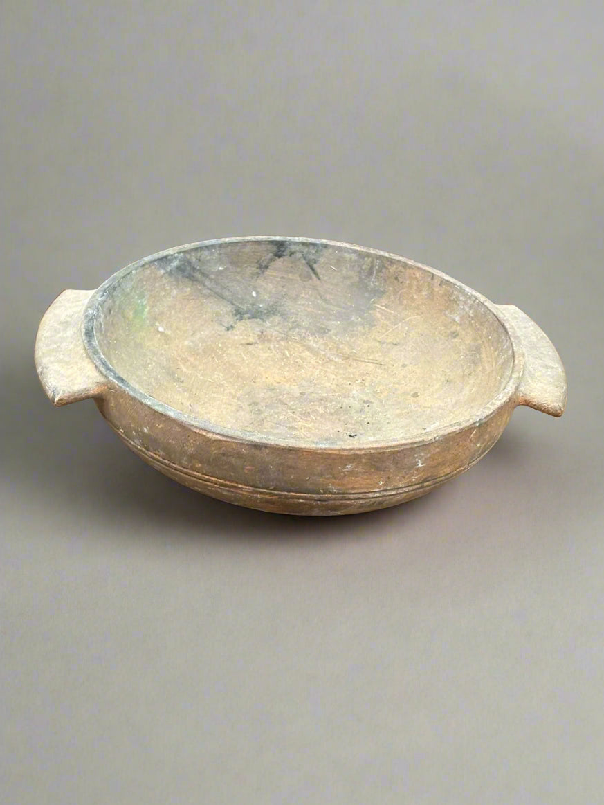 An antique, rustic, round, wooden dough/kitchen bowl with flat handles.