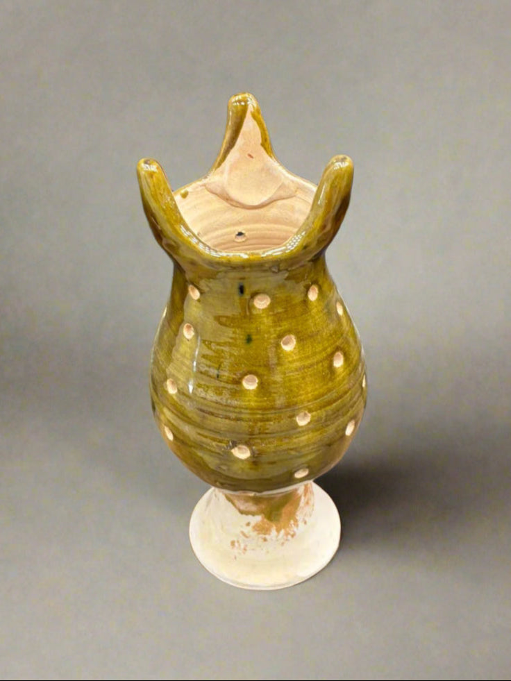 A green earthenware tealight holder with holes, finished with a glossy glaze.