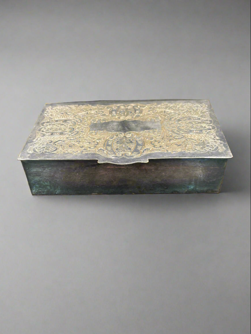 An antique silver cigarette/ jewellery box with an ornately engraved lid.