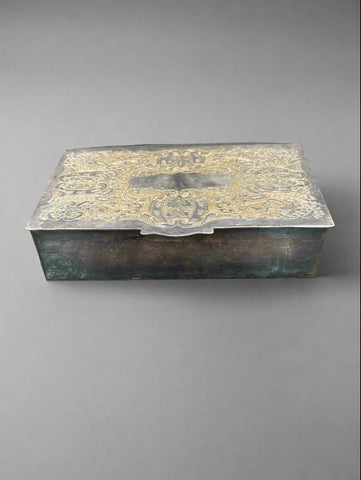 An antique silver cigarette/ jewellery box with an ornately engraved lid.