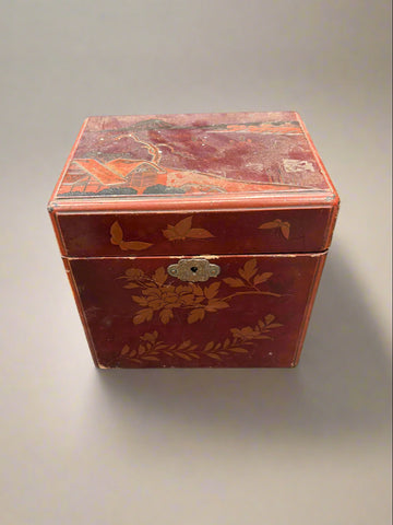 An antique Japanese jewellery box/ tea caddy with a red lacquer design.