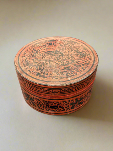 An antique Burmese betel nut box with an intricate red and black design.