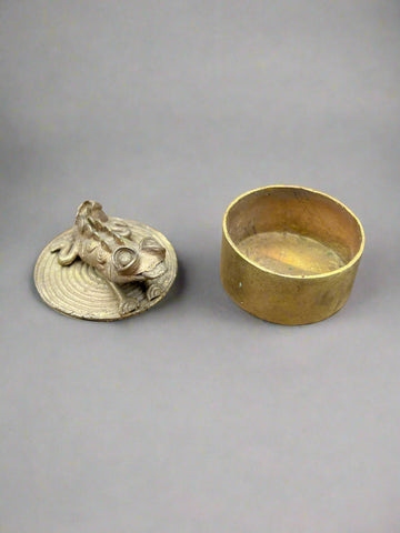 A small, handmade, brass trinket pot featuring a perched lizard/ chameleon on the lid.