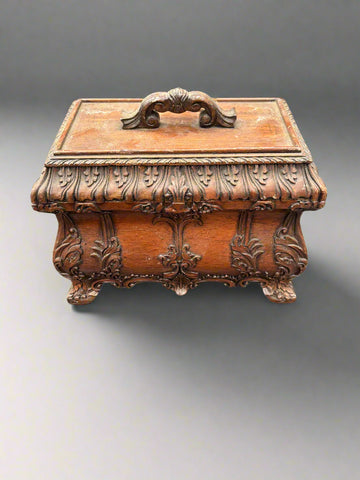 An antique, hand-carved, mahogany tea caddy/chest with ornate scroll details to the body and handle.