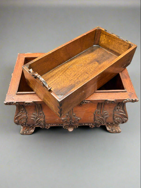 An antique, hand-carved, mahogany tea caddy/chest with ornate scroll details to the body and handle.