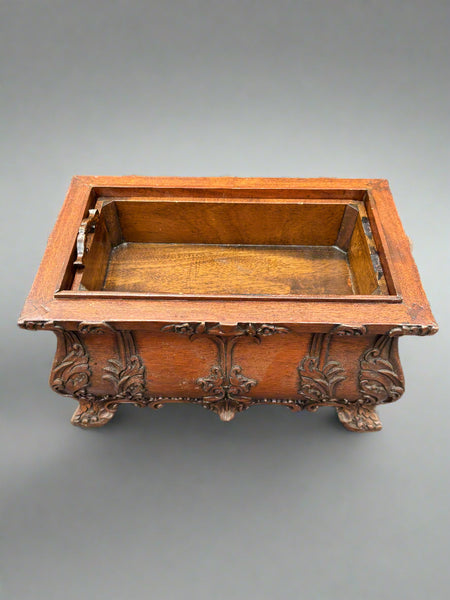 An antique, hand-carved, mahogany tea caddy/chest with ornate scroll details to the body and handle.