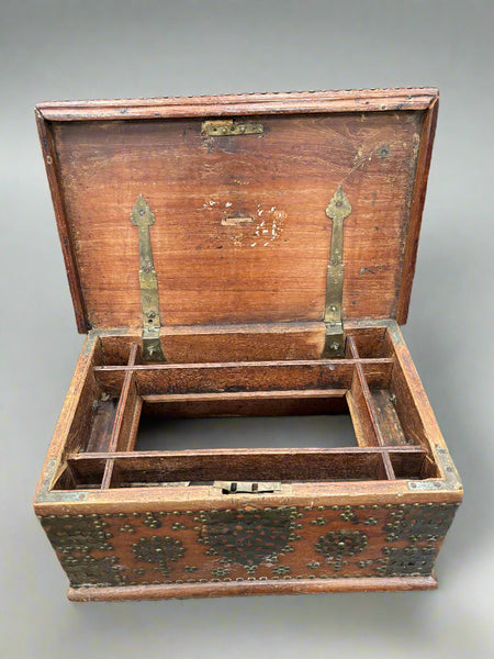 An antique brass bound Zanzibar chest with metal stud detailing and a sectioned interior.