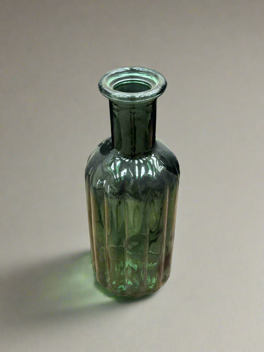 A small, ribbed, emerald green, glass bud vase.