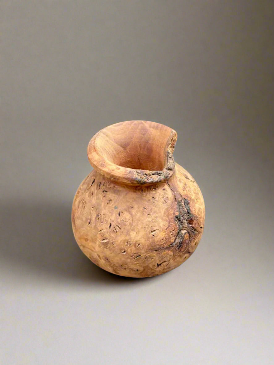 A natural circular wooden paint brush pot.