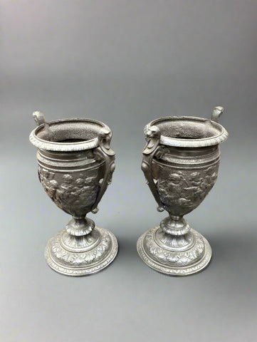 A pair of antique, neoclassical, pewter urn vases with cast cherub decoration, circa 19th century.