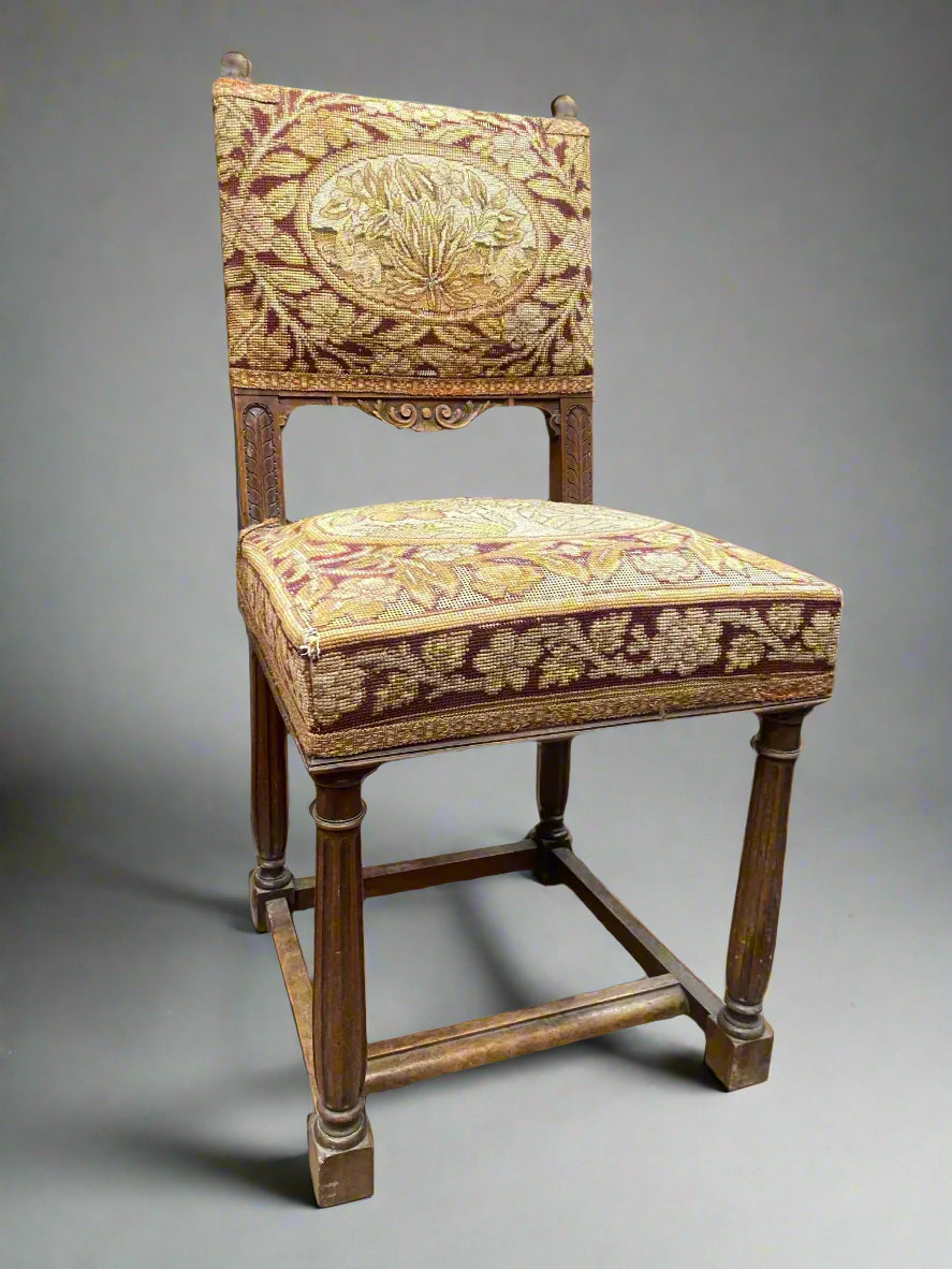 An antique dining chair upholstered with red and yellow tapestry-style fabric.