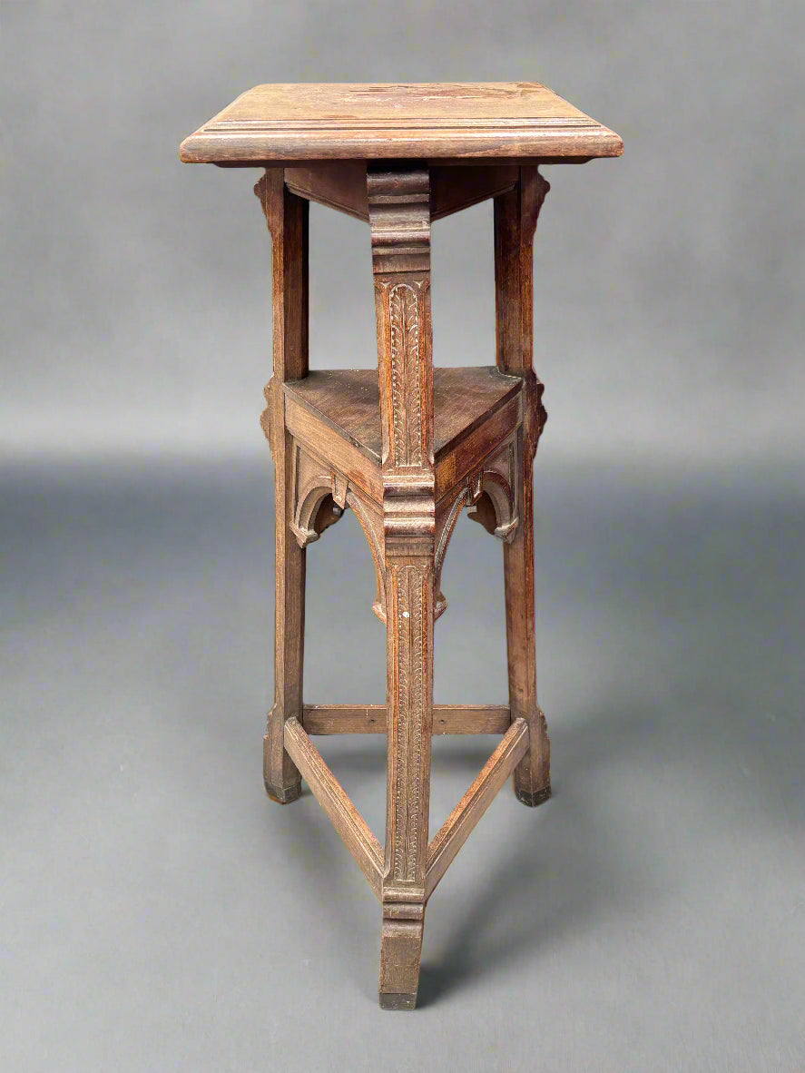 An antique Neo-Gothic pedestal stand with a triangular structure and decorative carved legs.