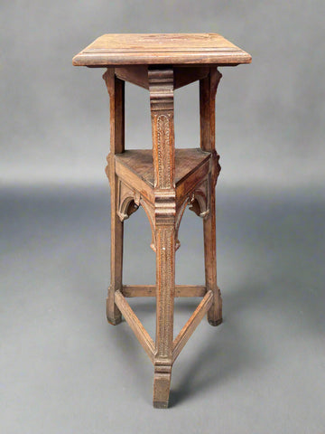 An antique Neo-Gothic pedestal stand with a triangular structure and decorative carved legs.