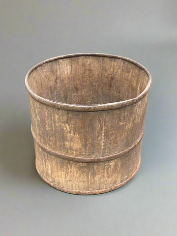 A large, round, rustic, staved planter in the style of a barrel. It could also be a butter bucket.