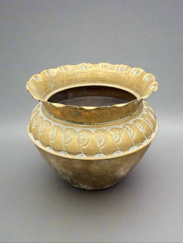 An antique, round, brass jardiniere with a crimped edge and decorative wave-like pattern.