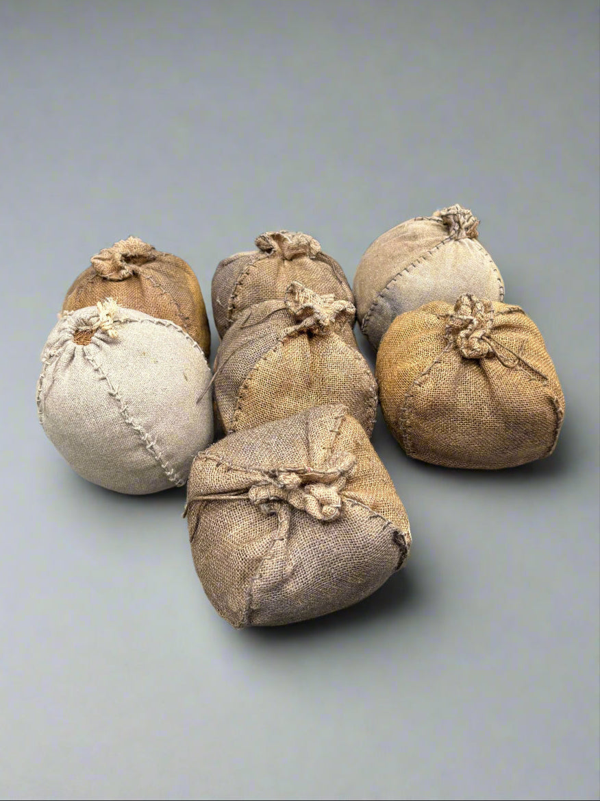 A set of small, hand stitched, burlap bundles, stuffed with hay.