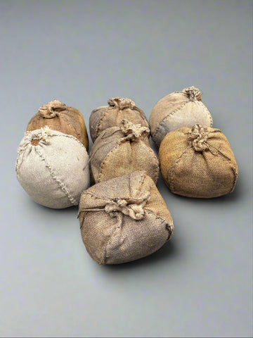 A set of small, hand stitched, burlap bundles, stuffed with hay.
