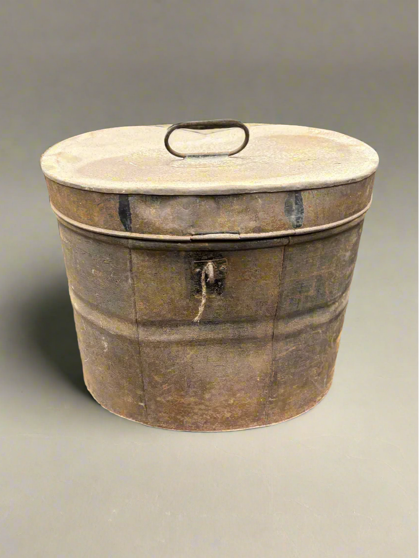 A rusty Victorian metal hat/wig box, circa 19th century. It could also be a military helmet box.