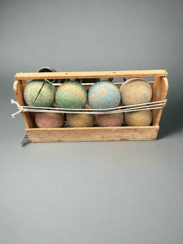 An antique French boules set with muted pastel colours, in a wooden carrier. Circa 1900s.
