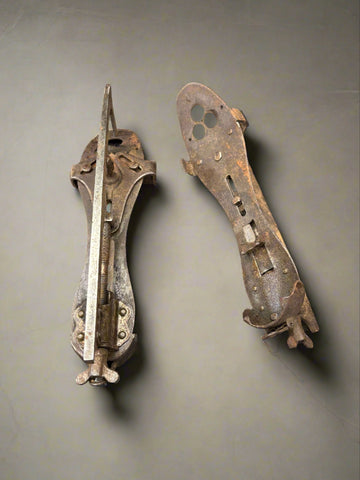 A pair of antique, metal, clip-on ice skates with an adjustable base.