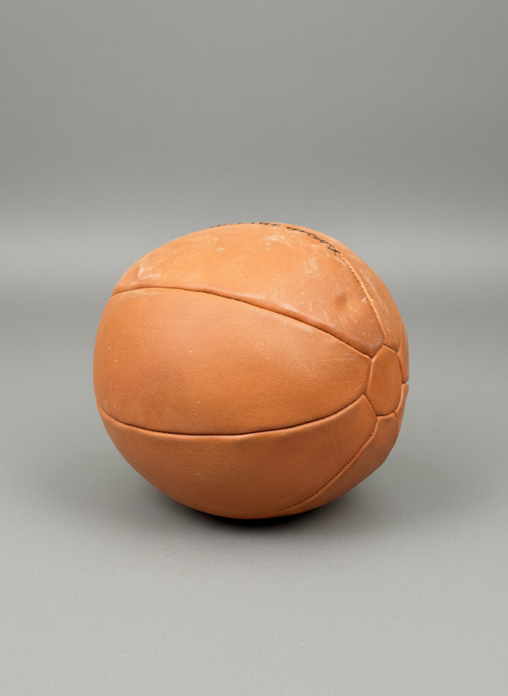 A vintage-style, light brown, leather medicine ball.