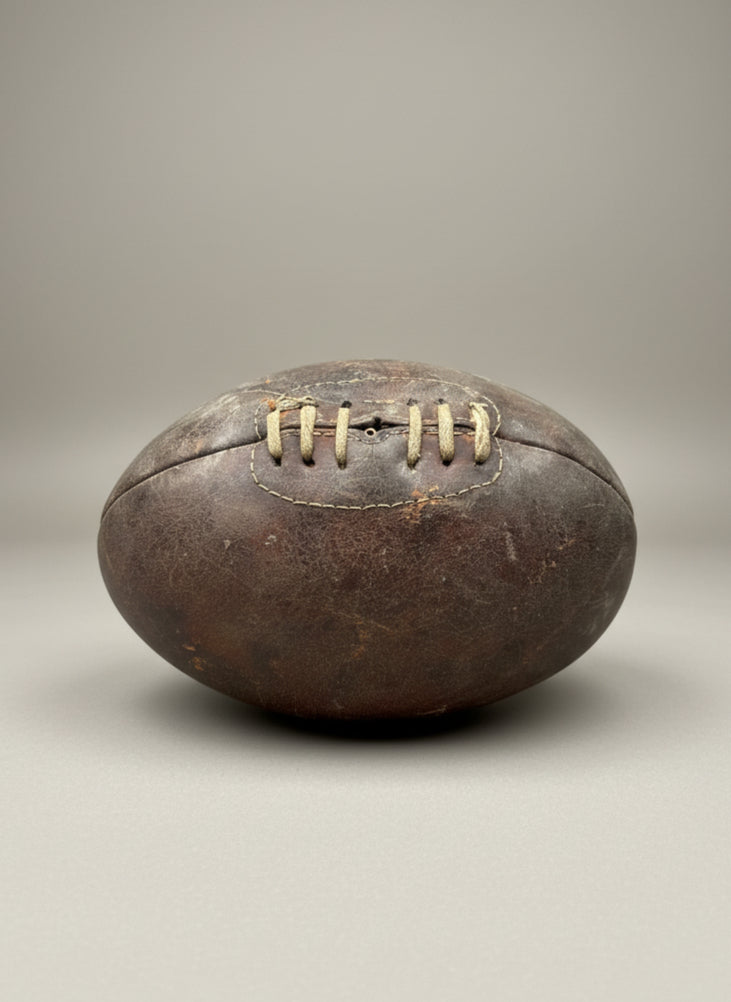 A vintage, worn leather rugby ball with a laced front, circa 1940s.