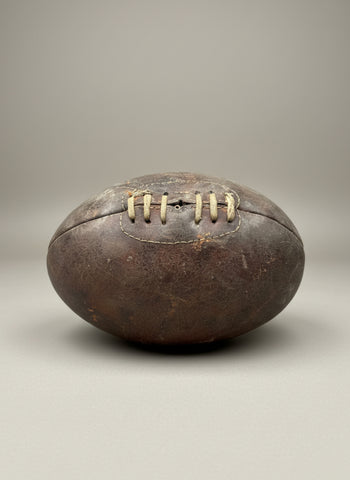 A vintage, worn leather rugby ball with a laced front, circa 1940s.