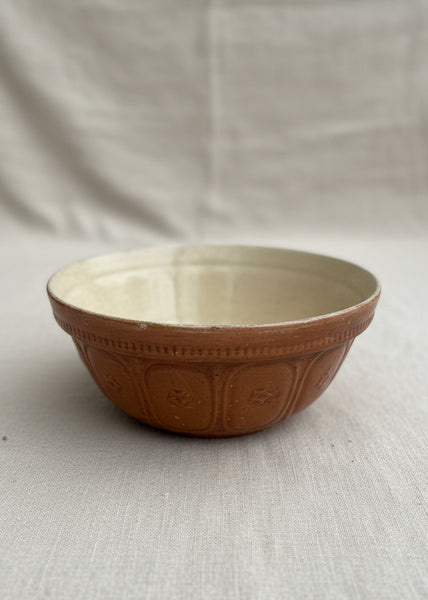 A pair of Hartley's stoneware mixing bowls with a mid brown glaze, circa 1930s. They're moulded on the outside with panels featuring a centre flower design.