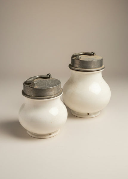 A pair of antique French bouillon soup jars with pewter lids and ironstone/ porcelain bodies, circa 19th century. The holes in the base are to hang the jars upside down in boiling water.