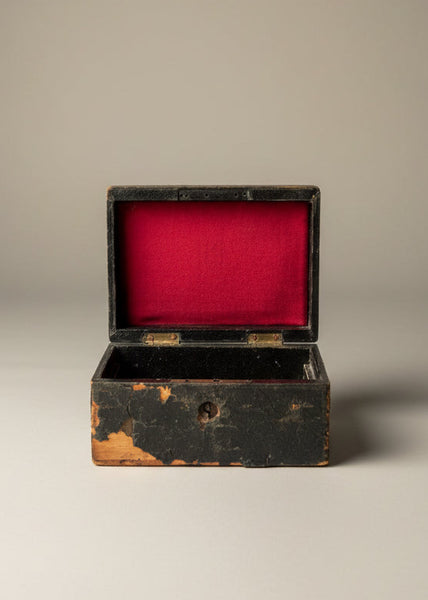A small antique red-lined storage box with a cracked cover.