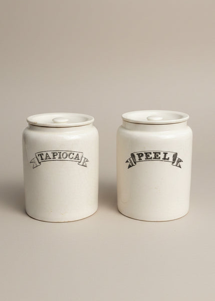 A set of vintage white ironstone kitchen storage jars with a scroll font label.