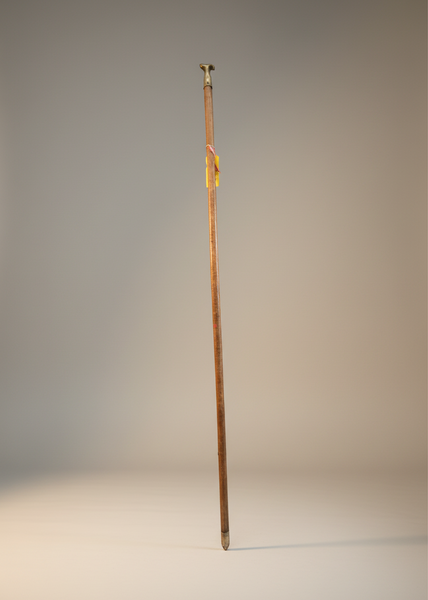A brass window opening hook on a long wooden pole.