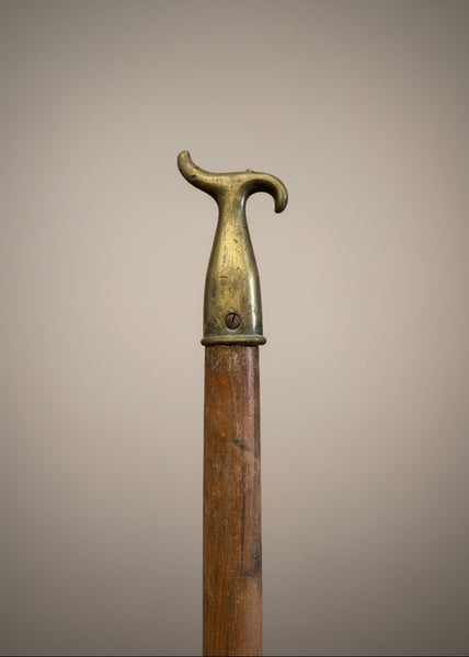 A brass window opening hook on a long wooden pole.