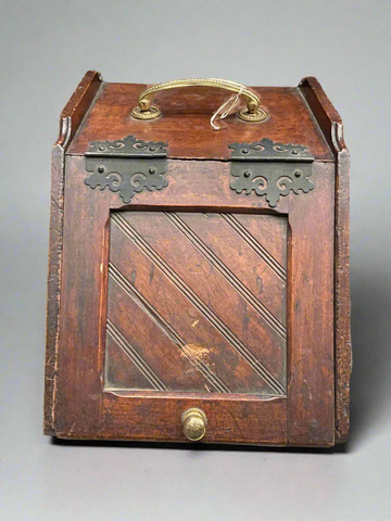 Wooden purdonium coal scuttle with brass hardware. The inside is filled with coal.