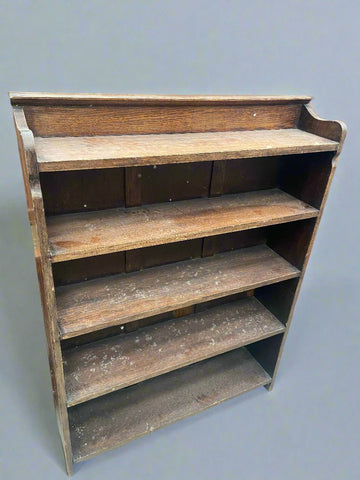 Simple wooden bookcase with five shelves, in an aged condition.