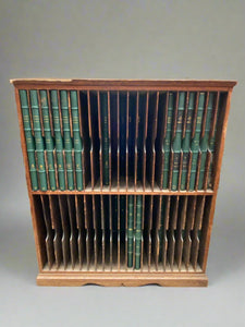 Large wooden bookcase crafted to display a set of large green antique books.