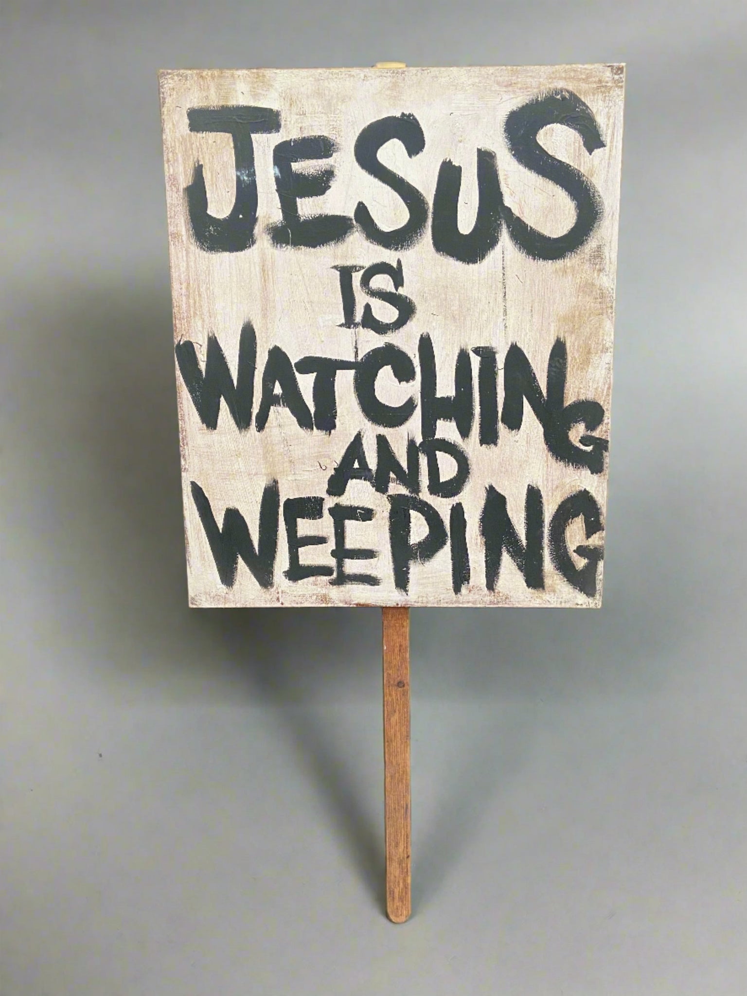 'Jesus is watching and weeping' hand-held wooden sign.
