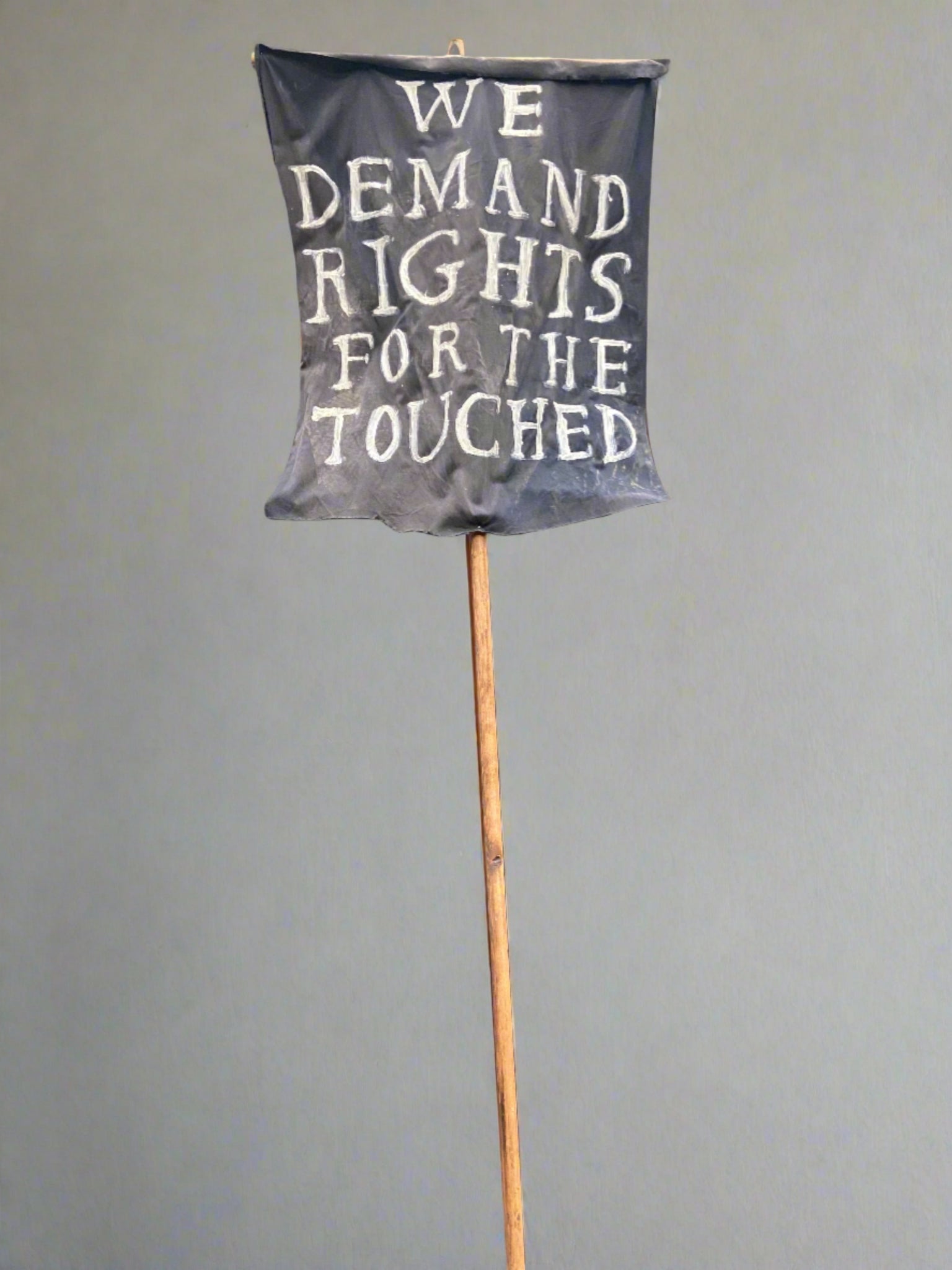 'We demand rights for the touched' hand-held fabric sign mounted on a wooden pole.