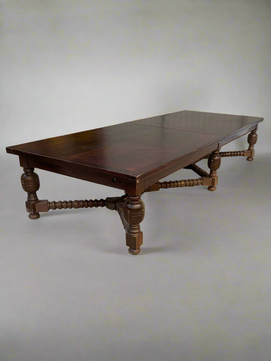 A huge, antique, rectangular, wooden dining table with heavily turned legs.