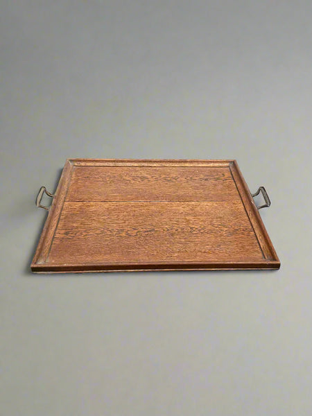An antique, oak, square serving tray with curved brass handles.