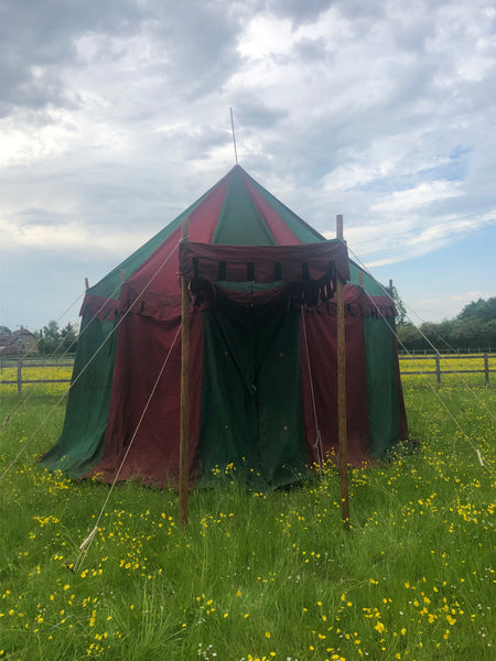 Medieval style jousting tournament tent in red and green with canopied entrance.