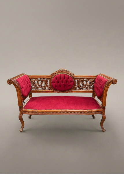 A Victorian-style carved mahogany settee with crimson pink upholstery.