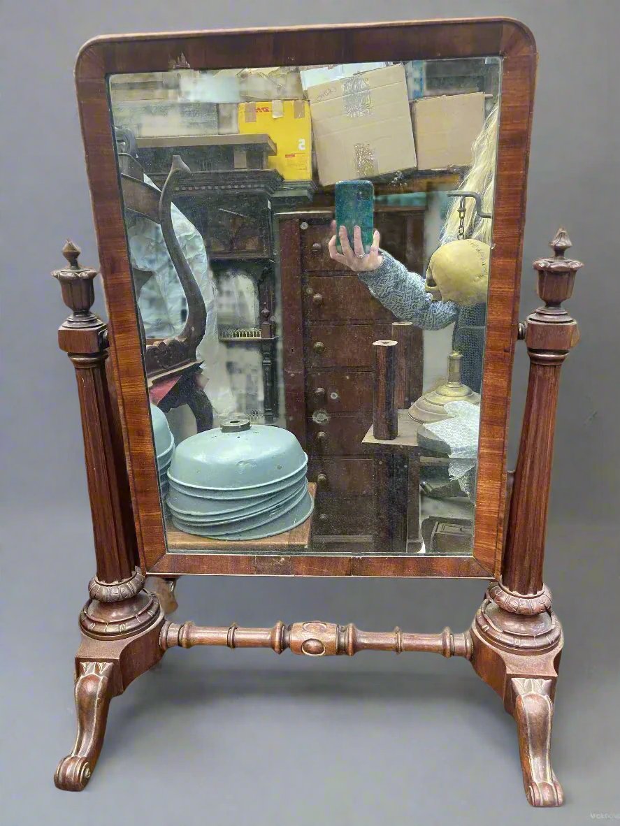 Curved rectangular vanity mirror supported by two ornate wooden legs.